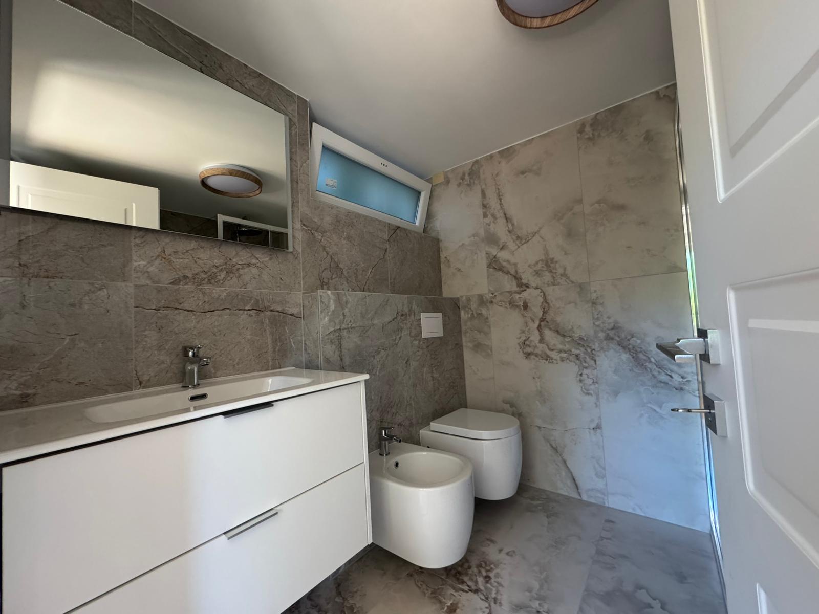 Bagno rivestito in gres effetto marmo con mobile sospeso