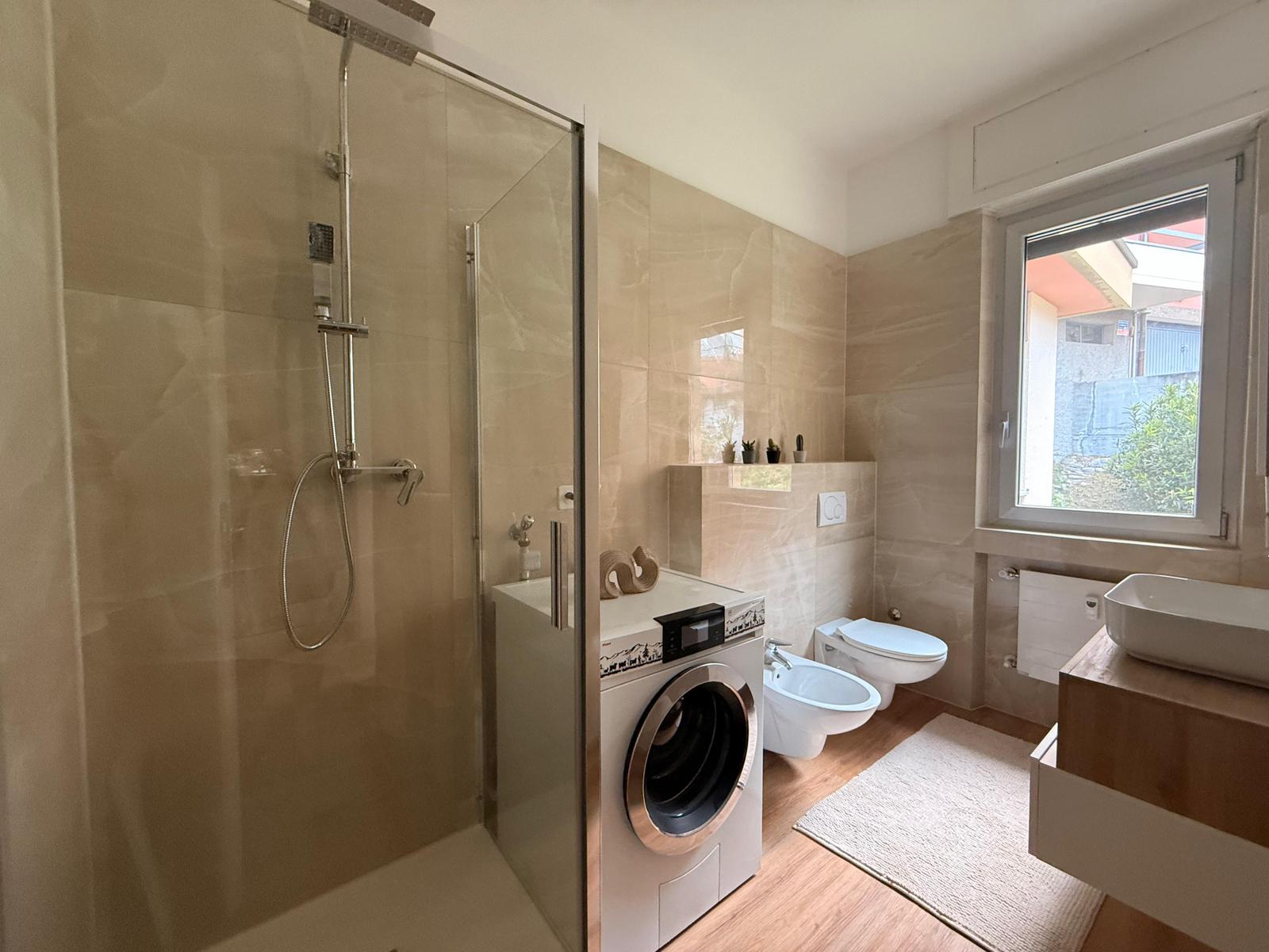 Bagno moderno con doccia in vetro e rivestimento effetto marmo